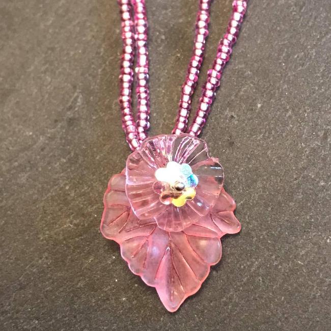 Necklace made from pink seed beads with a flower and leaf pendant.