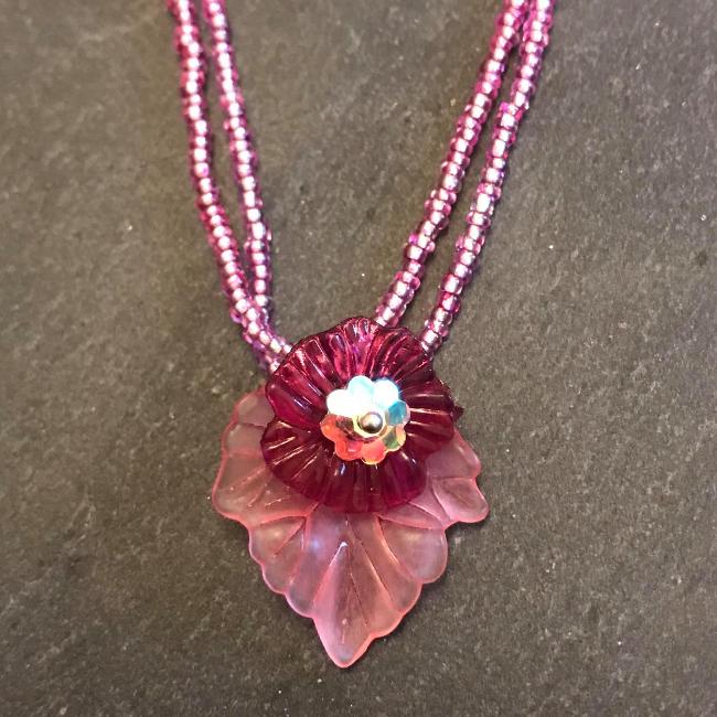 Necklace made from pink seed beads with a flower and leaf pendant.